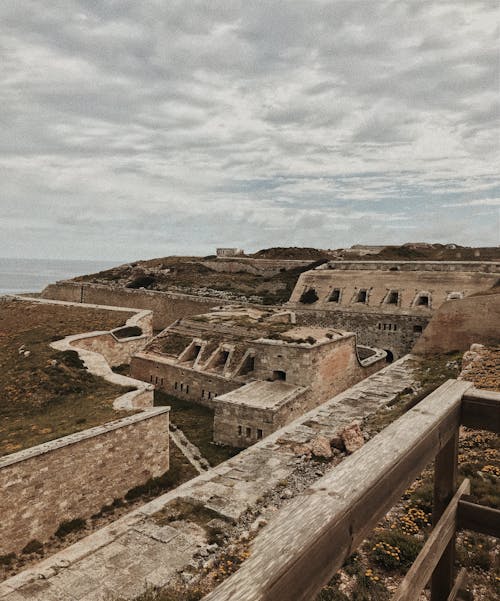 Mola fortress with aged stone construction located against cloudy sky in Spain on coastal area near rippling sea in nature
