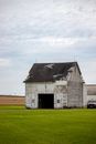 Gray Wooden House on Green Grass Field Under White Clouds