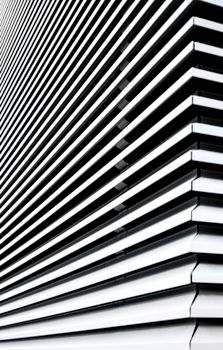 Black and white close-up of modern window blinds creating abstract geometric patterns.