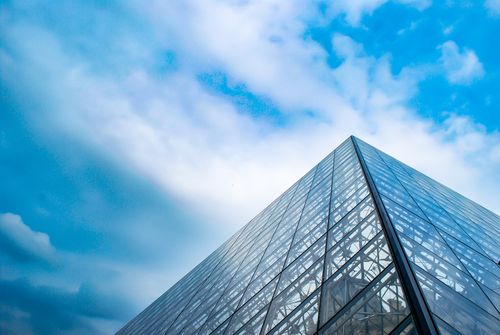 Free Low angle view of the Louvre Pyramid in Paris with a striking blue sky backdrop. Stock Photo