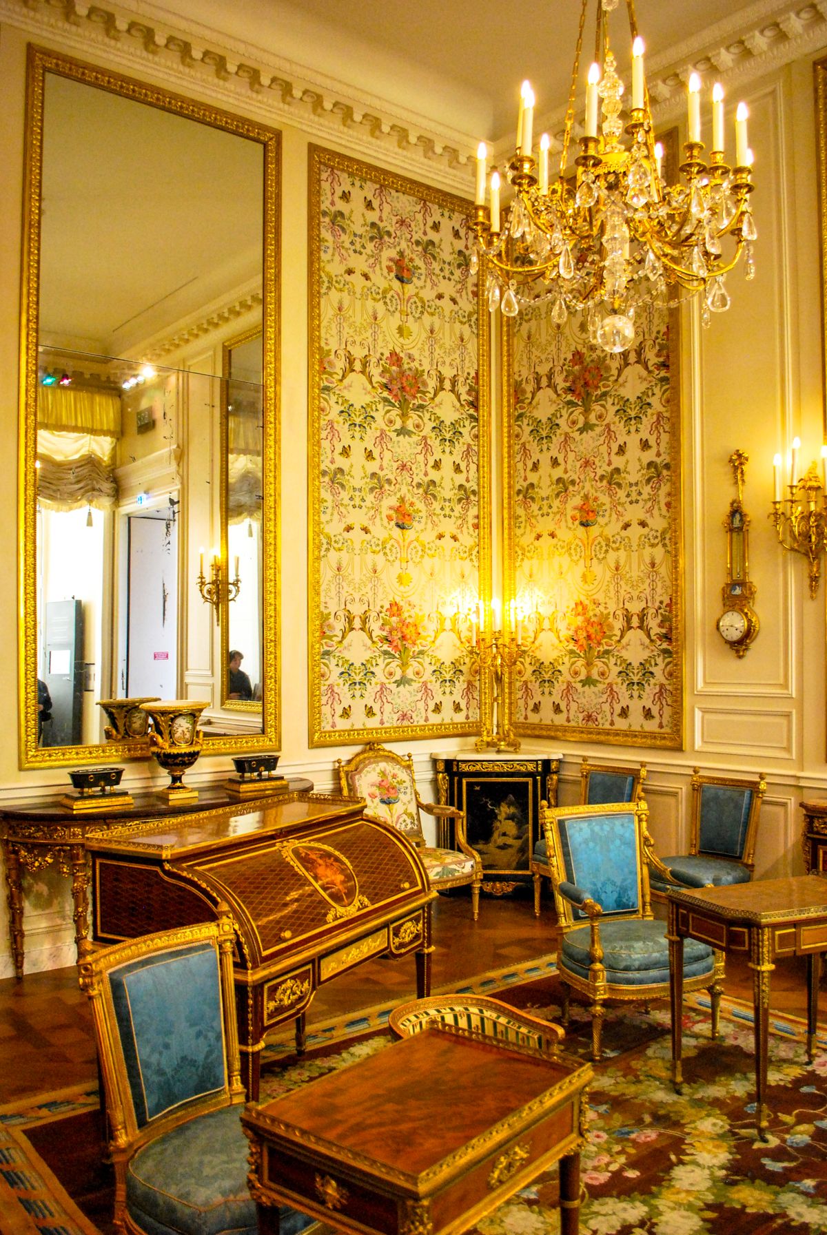A grand parlor room with gilt-framed art and a crystal chandelier