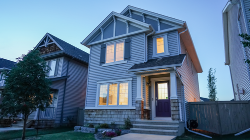 Free Charming modern suburban house with illuminated windows at dusk, featuring sleek architecture and wooden accents. Stock Photo