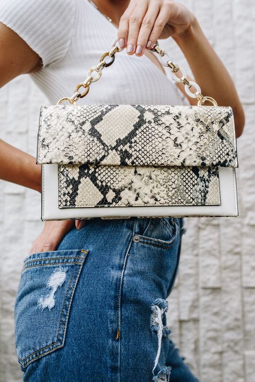 Free Close-up of a woman showcasing a trendy snakeskin handbag against a textured wall. Stock Photo