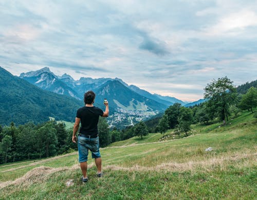 Man Standing on Hill Near Forest