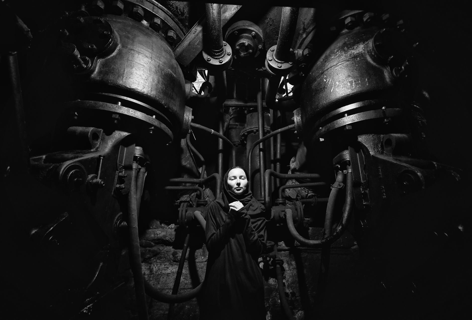 Moody black and white portrait inside an industrial plant with machinery.