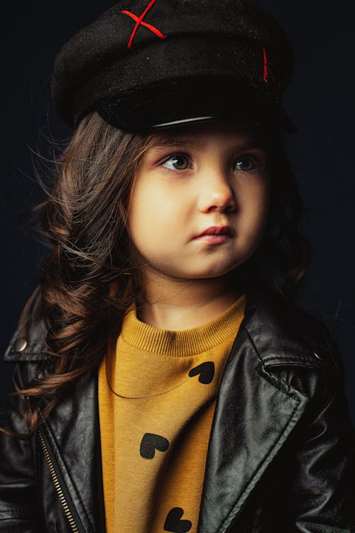 Close-Up Photo of a Kid in a Mustard Sweater Looking Away