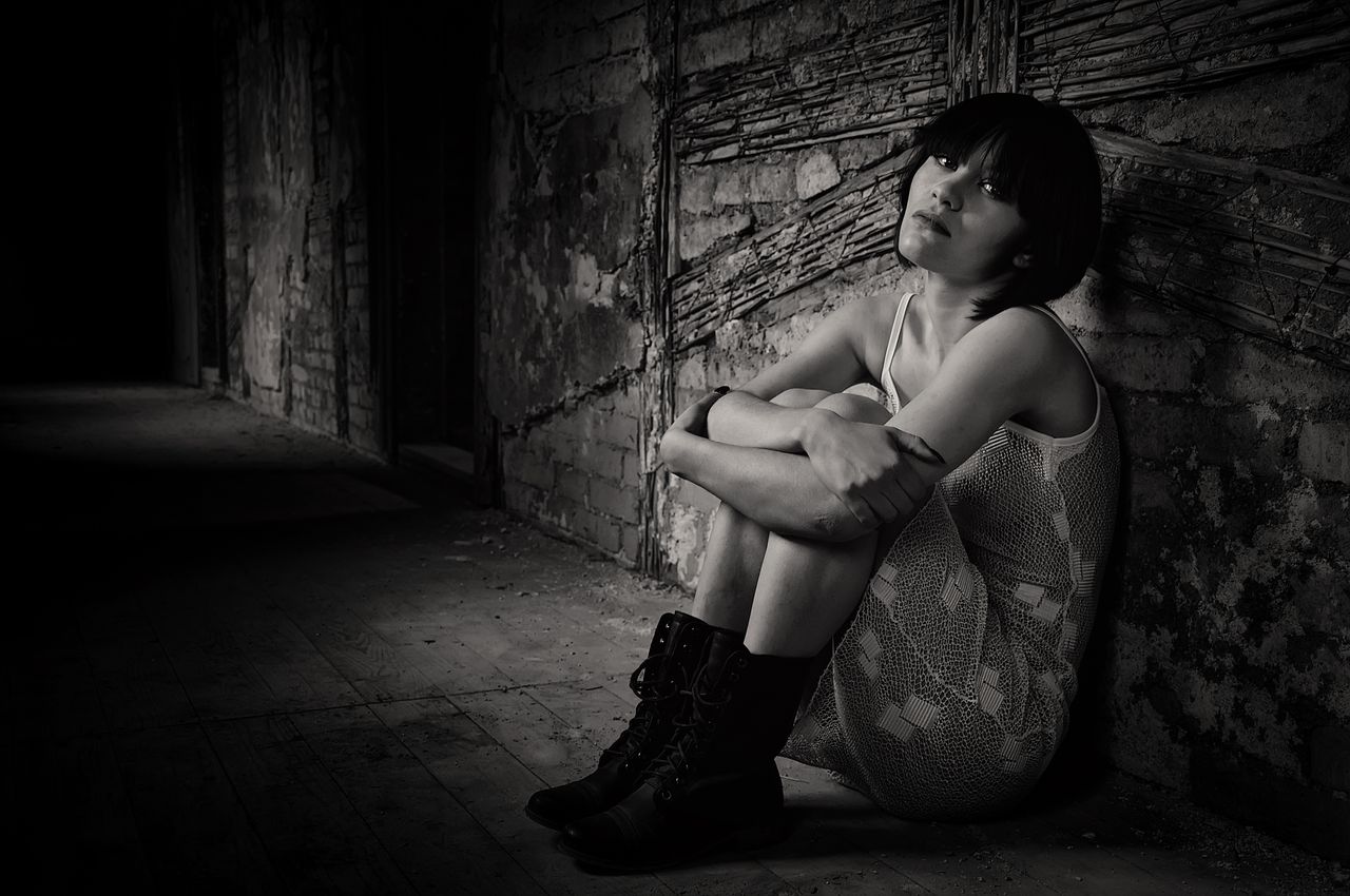 black and white portrait of a woman sitting in an abandoned building m