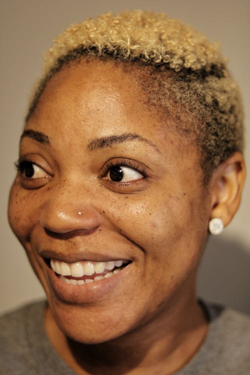 Cheerful black woman with blond hair and earrings