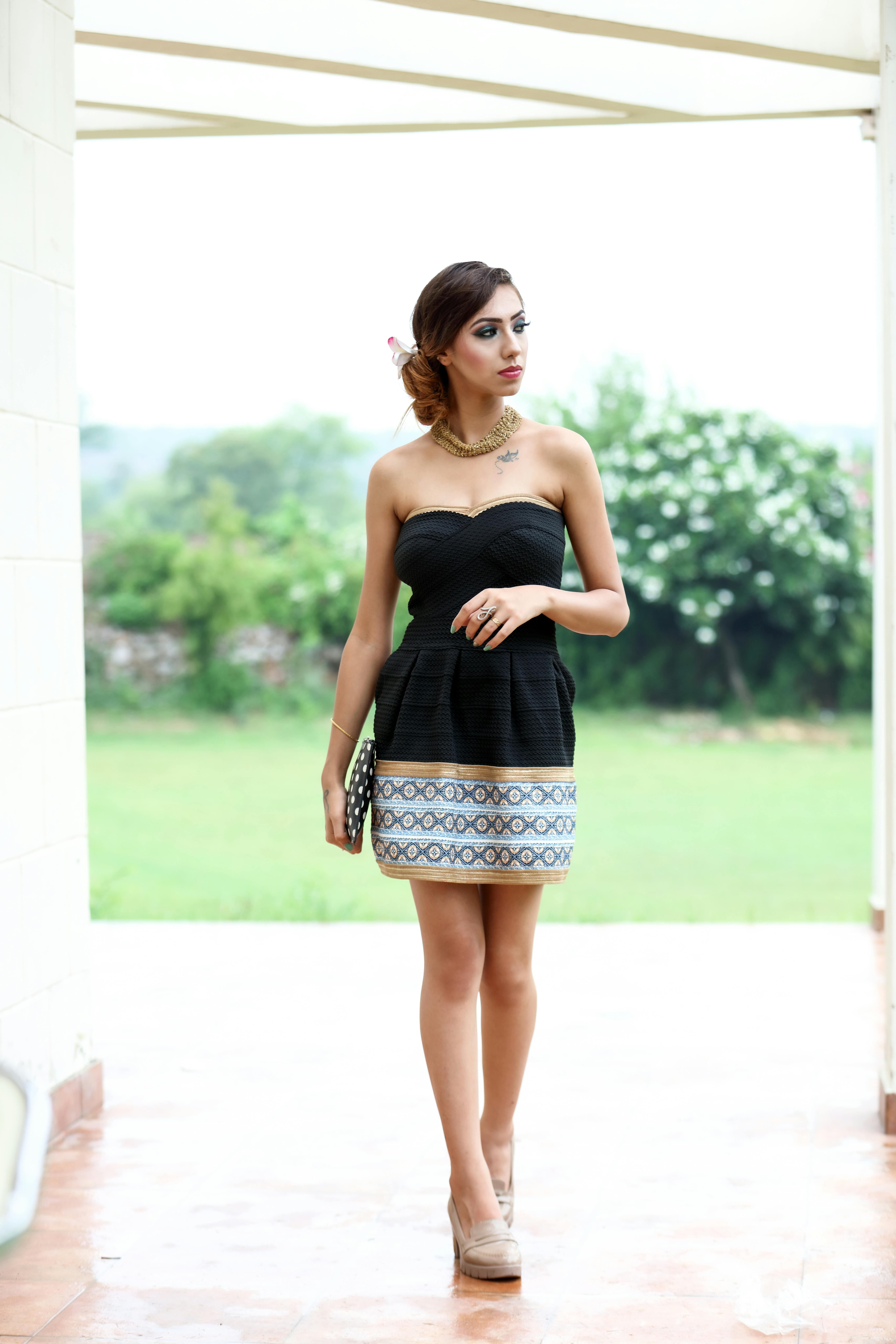 Female in dress on veranda near grassy meadow with plants