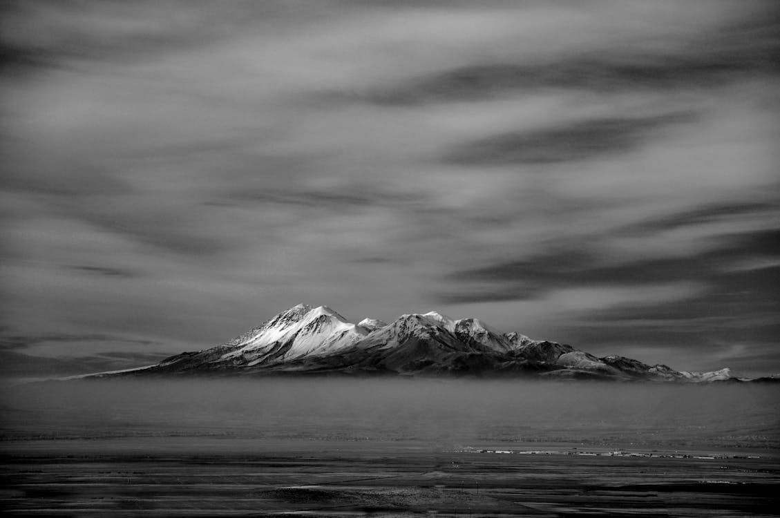 Grayscale Photo of a Mountain Under a Cloudy Sky