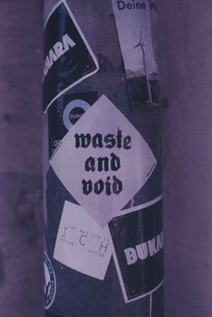 Close-up of a metal post covered in urban stickers with moody lighting.