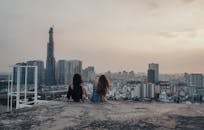 Woman in Black Jacket Sitting on Gray Concrete Floor Near Woman in Red Jacket