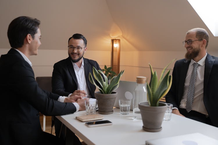 A Group Of Men In Black Suit Sitting Near The Table While Having Conversation