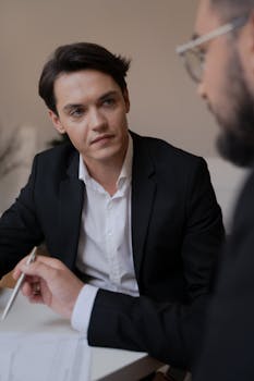 Two men in a business meeting, engaged in discussion at an office table.