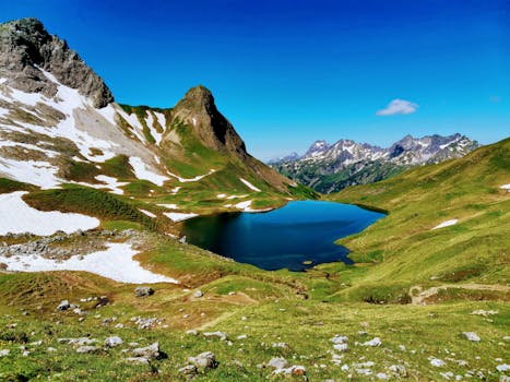 Stunning view of a serene alpine lake surrounded by snowcapped mountains in Warth, Austria. Perfect landscape for nature lovers.