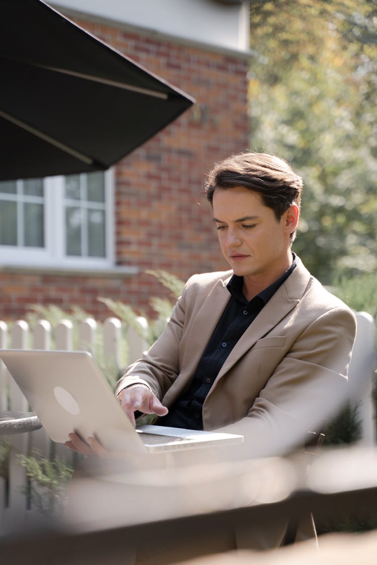 Man In Beige Suit Coat Using A Laptop