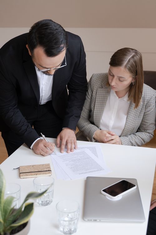Free Two business professionals signing a contract at a desk; collaborating in an office. Stock Photo
