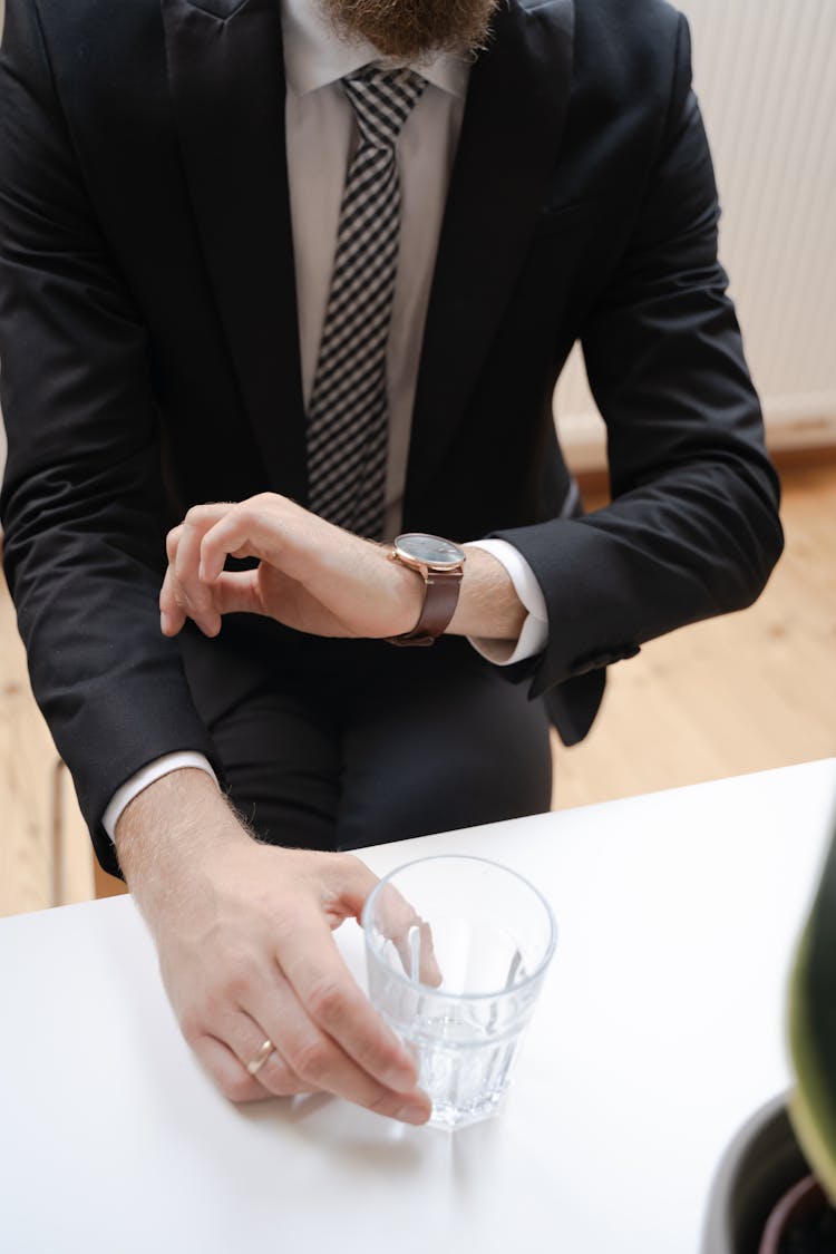 A Man In Black Suit Jacket Holding Clear Drinking Glass