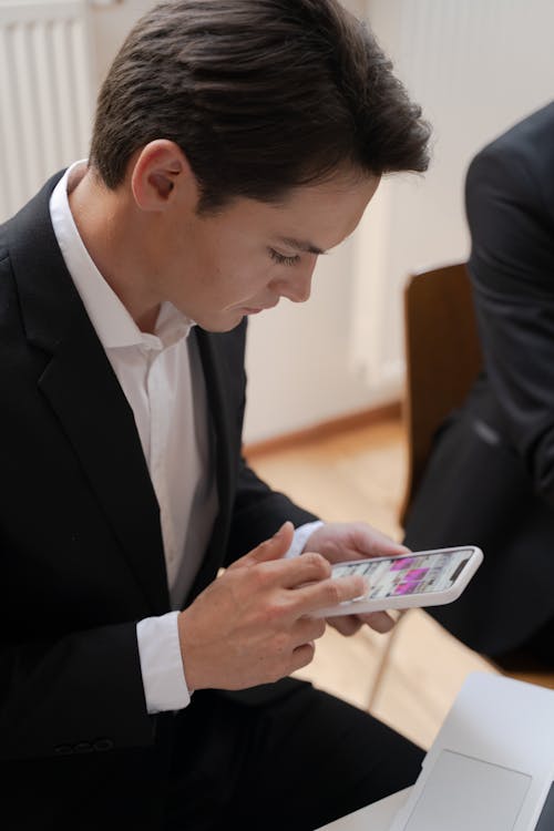 A Man in Black Suit Jacket Holding a White Smartphone