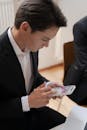 A Man in Black Suit Jacket Holding a White Smartphone