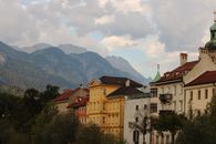 White and Brown Concrete Building Near Green Trees and Mountains Under White Clouds and Blue Sky