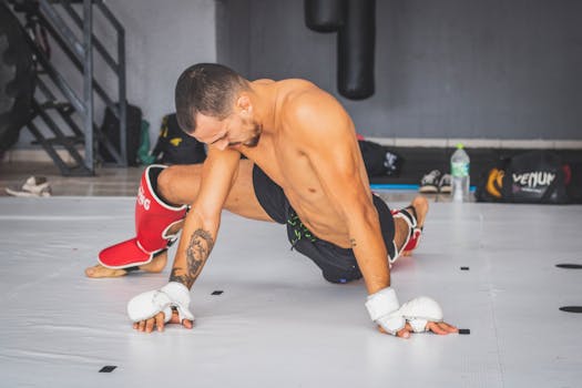 Male athlete stretching and warming up on a gym mat before training session. Sports focused.