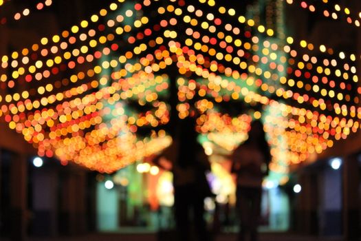Blurred bokeh lights create a vibrant, festive atmosphere on a nighttime city street.