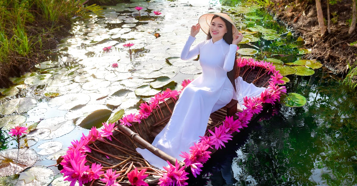 Woman in a White Dress Sitting on a Boat with Pink Water Lilies · Free ...