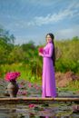 Woman in Brown Long Sleeve Dress Holding Pink Flower