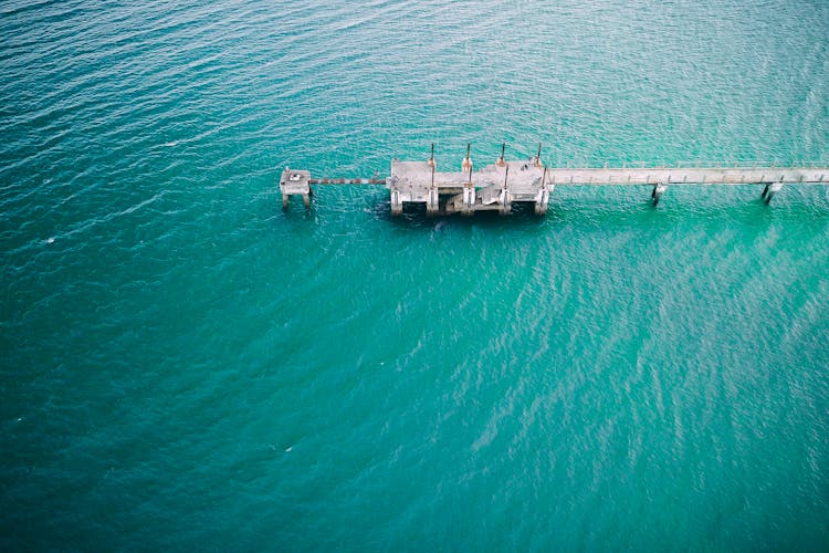 Long Gray Concrete Pier Surrounded With Rippling Water