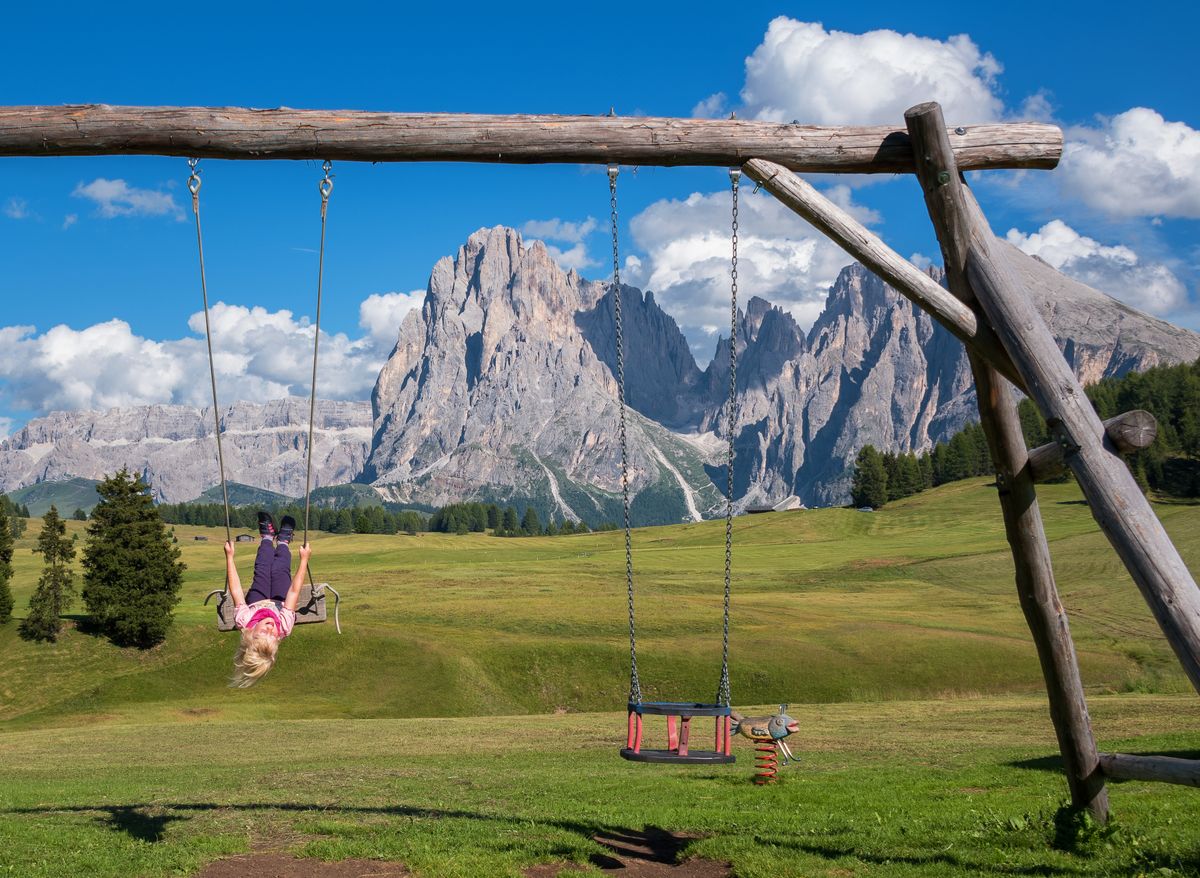 Playground swing with alpine mountain backdrop