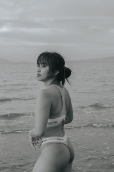 Artistic black and white photo of a woman in swimwear on a beach.