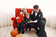 一家人穿着万圣节服装，在室内围着南瓜庆祝节日