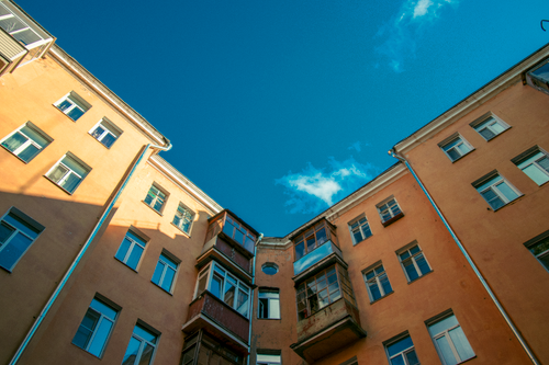 Free From below of aged residential house with windows and balconies located in living complex against blue sky Stock Photo