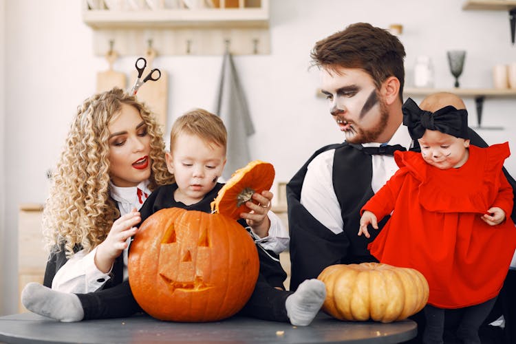 
A Family In A Halloween Costume Looking At Pumpkins