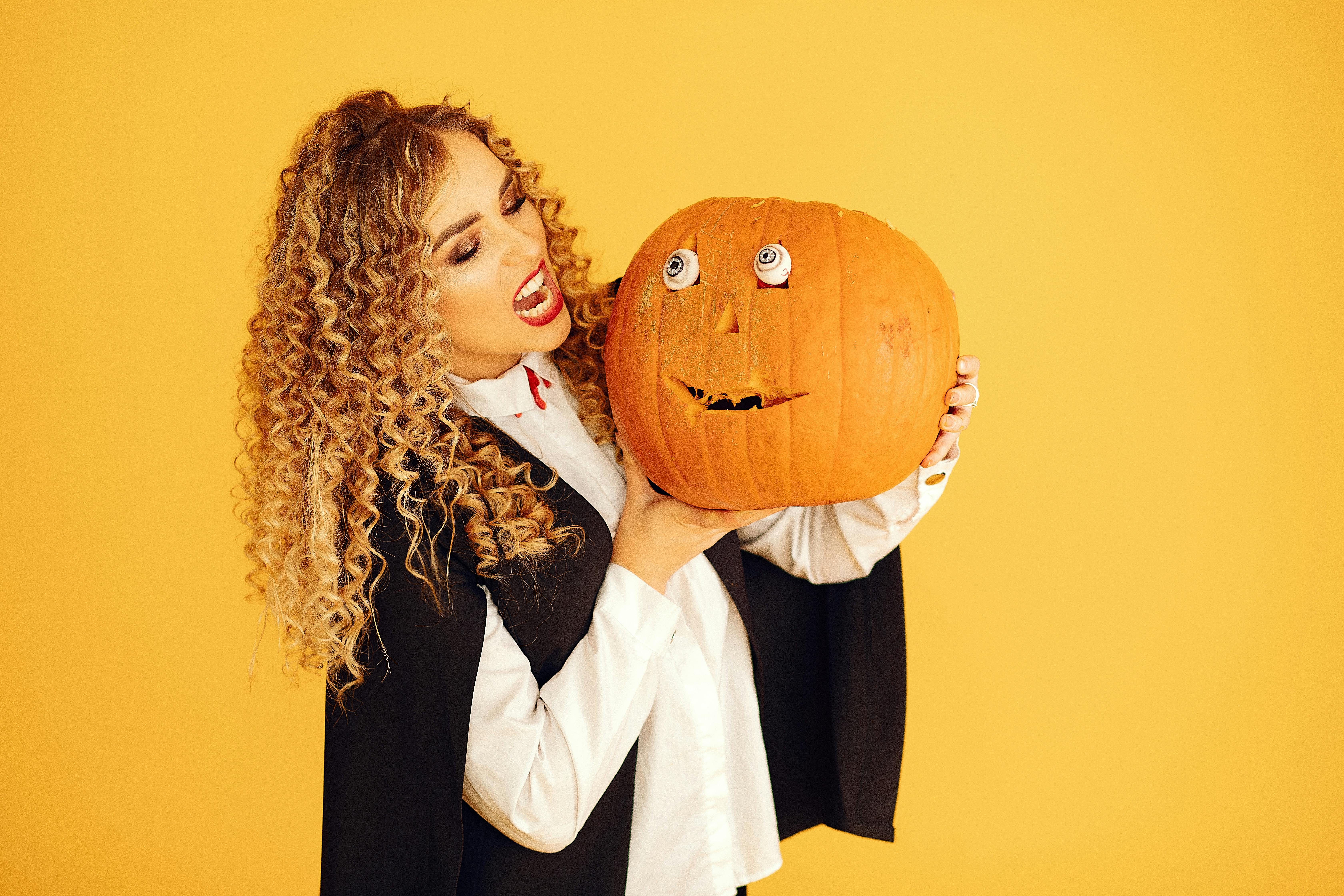 woman in halloween costume holding jack o lantern