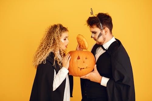 Free Man in Black Suit and Woman Holding Jack O Lantern and Opening Its Head Stock Photo