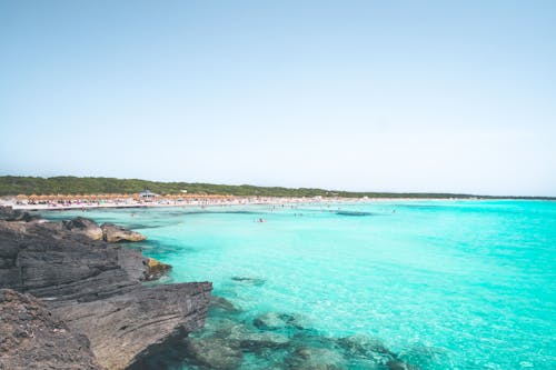 Rocky Shore Beside Blue Sea Water Under Blue Sky