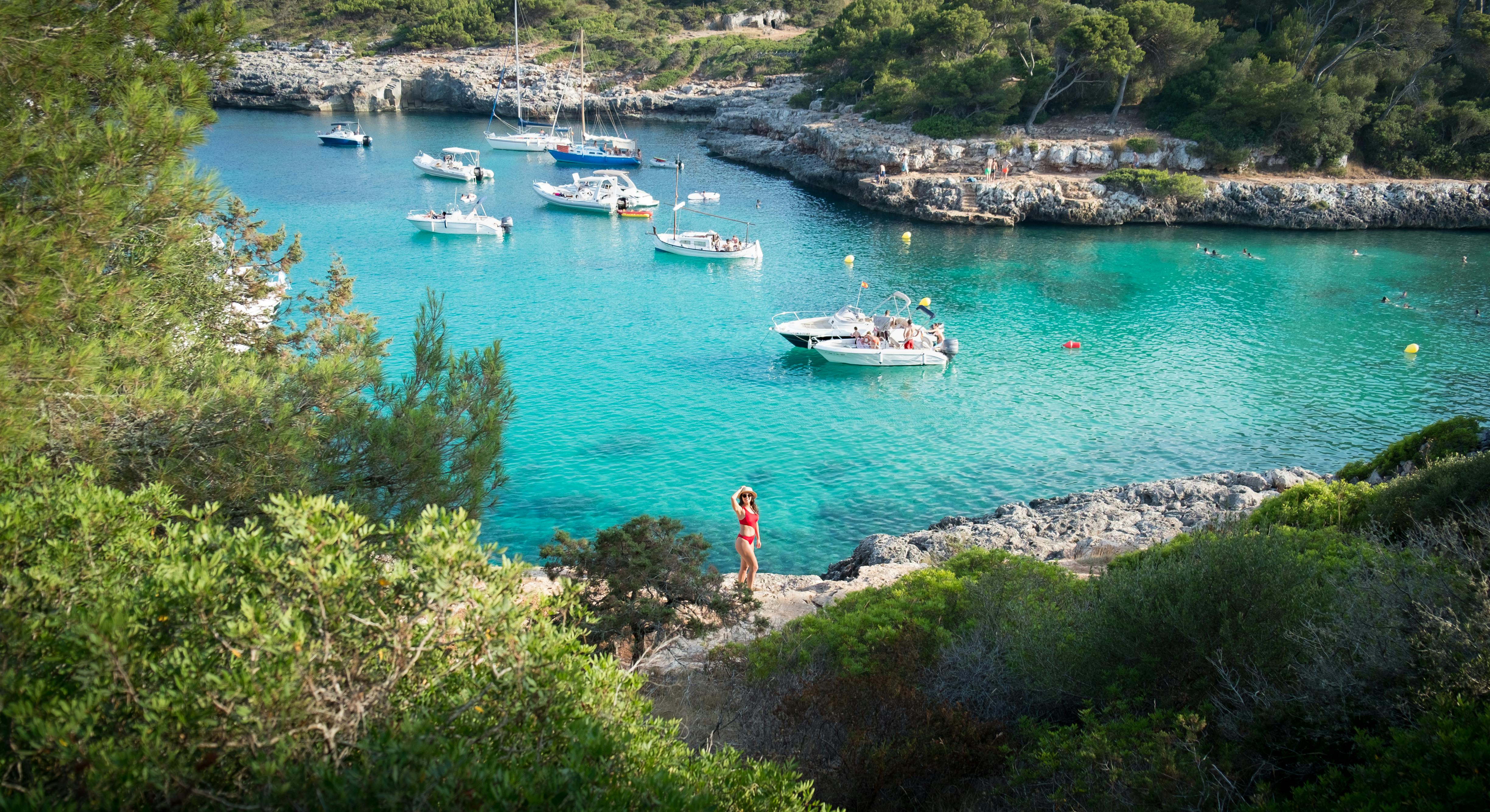 Woman in red bikini standing on the shore besides water