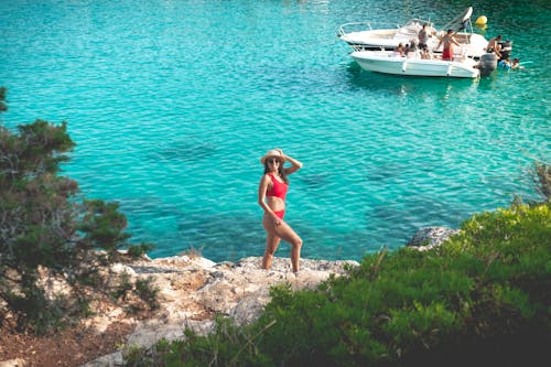 Woman in Red Bikini Standing on Rock Near Water