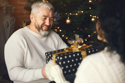 Free Smiling Husband Receiving a Christmas Gift from His Loving Wife Stock Photo