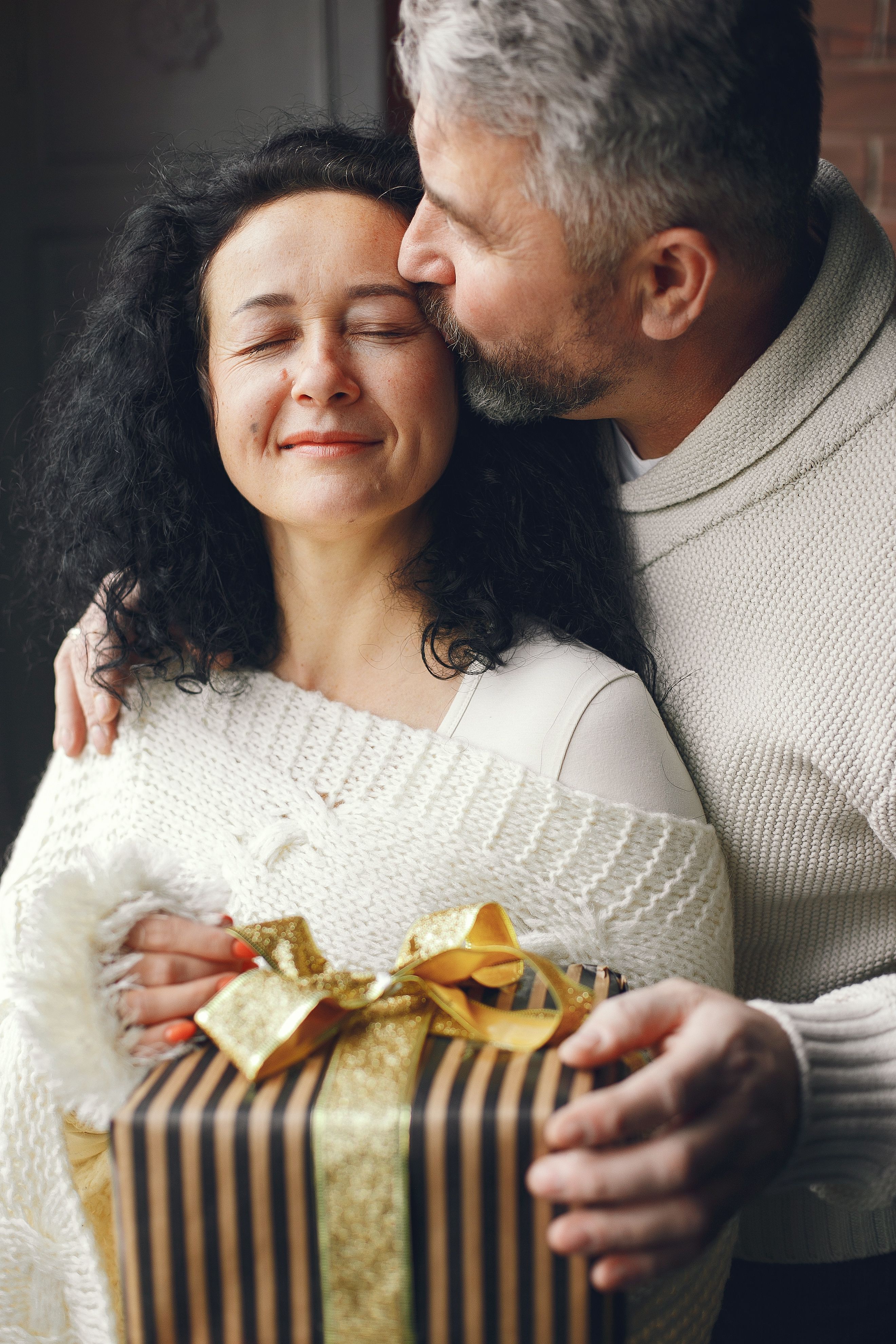 Loving couple exchanging a beautifully wrapped present indoors, capturing affection.
