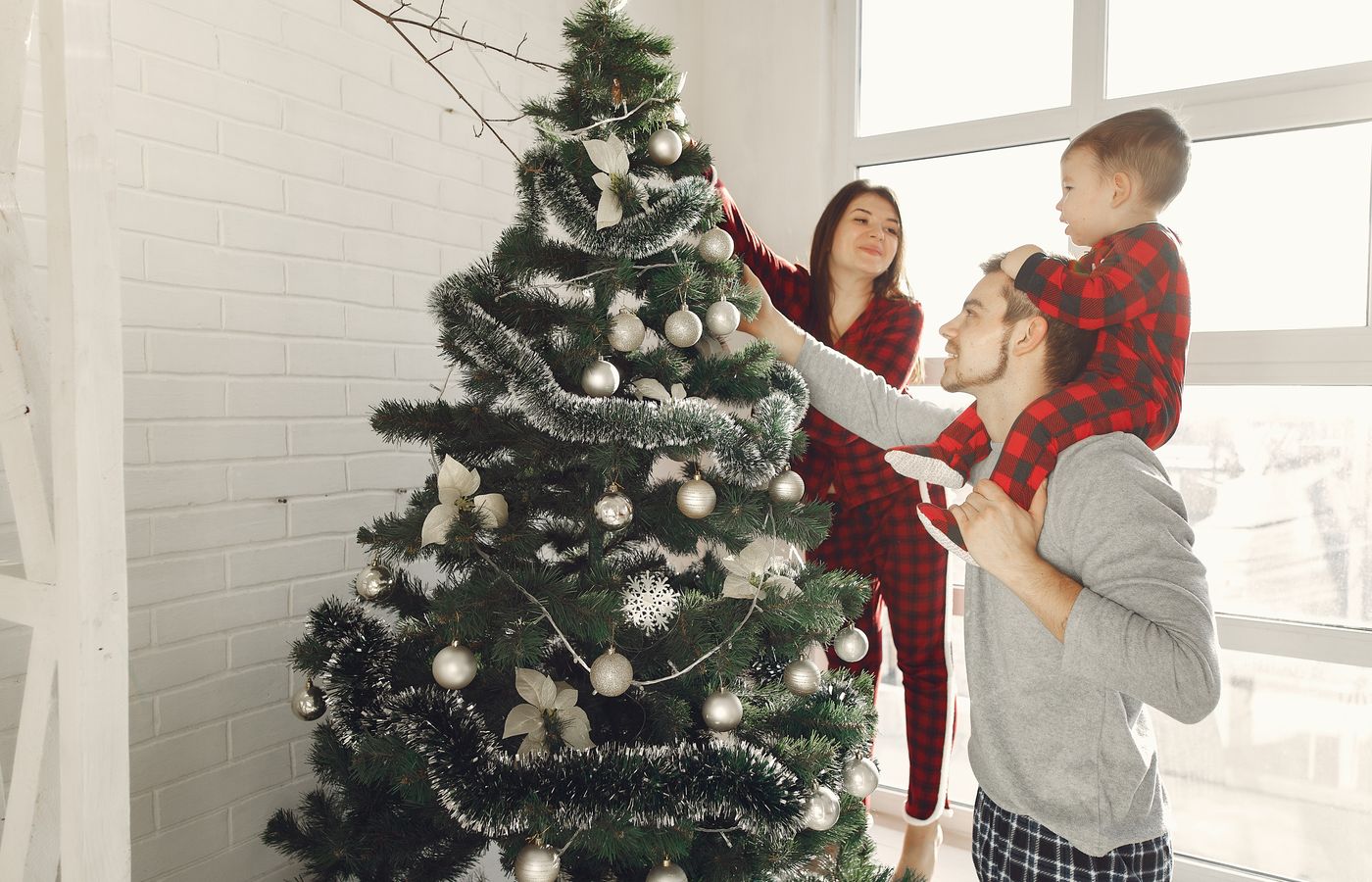 A happy family in pajamas decorates a Christmas tree, enjoying holiday togetherness.