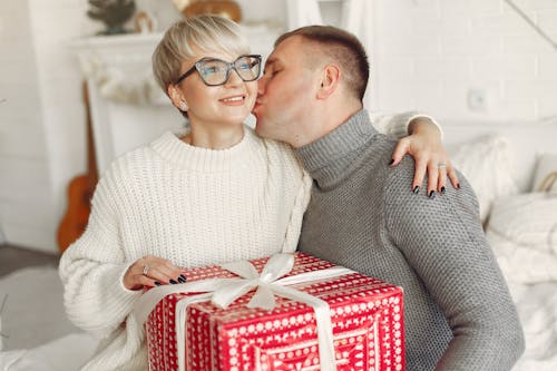 Man Kissing a Woman Holding a Present
