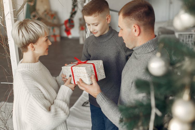 Mother And Father Giving Christmas Gift To Son