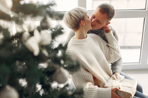 A Couple Kissing besides the Christmas Tree