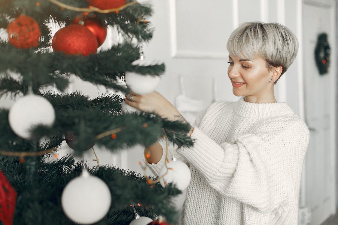 Woman Wearing White Sweater Decorating a Christmas Tree