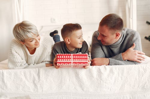 Boy with Present Lying on Bed with Parents