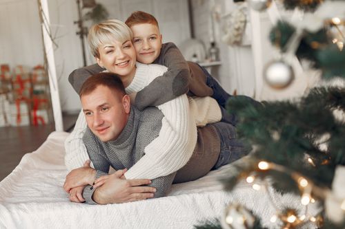 Free Happy family of three enjoying a cozy Christmas moment together indoors. Stock Photo