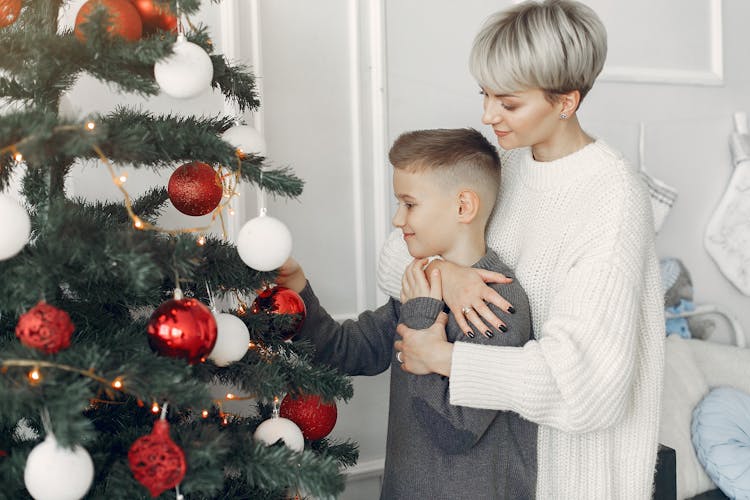 Mother And Son Decorating A Christmas Tree